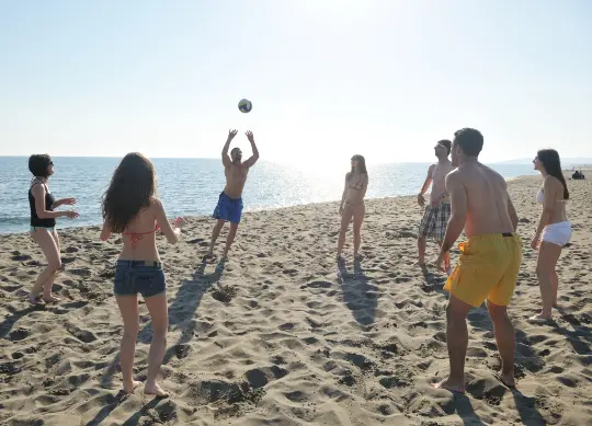Schülergruppe beim Volleyball spielen am Strand in Marseille Auf Klassenfahrt mit HEROLÉ: Nutzen Sie die Sonnenstunden für eine runde Volleyball am Strand in Marseille