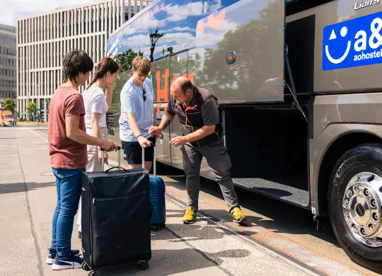 Busfahrer verstaut Gepäck im Reisebus bei einer Gruppenreise Sicheres Verladen der Gepäckstücke bei einer Klassenfahrt