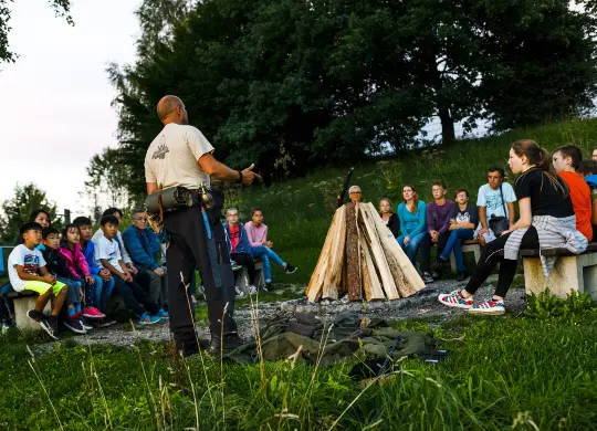 Tegernsee Schliersee Auf Klassenfahrt mit HEROLÉ: Reisegruppe und Guide sitzen um ein Lagerfeuer