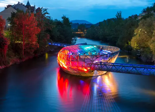 Auf Klassenfahrt mit HEROLÉ: Die Murinsel in Graz ist nachts bunt beleuchtet und ein beliebtes Fotomotiv.