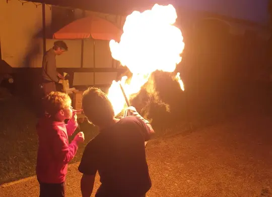 Auf Klassenfahrt mit HEROLÉ: Kind beim Feuerspucken beim erlebnispädagogisches Programm Nabedi Camp Eifel