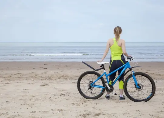 Auf Klassenfahrt mit HEROL&Eacute;: M&auml;dchen mit Fahrrad am Strand an der fl&auml;mischen Nordsee.