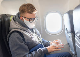 Junge mit Maske und Desinfektionstuch im Flugzeug Auf Klassenfahrt mit HEROLÉ: Ihre Sicherheit ist für uns das oberste Ziel.