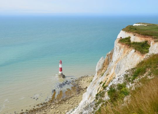 Blick von einer Felsklippe auf einen vorgelagerten Leuchtturm im Meer am Beachy Head in Eastbourne Auf Klassenfahrt mit HEROLÉ: Besuchen Sie auch den vorgelagerten Leuchtturm am Beachy Head in Eastbourne