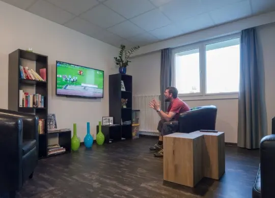 Auf Klassenfahrt mit HEROLÉ: Nyon Hostel - Chill-Out Raum mit Fernseher in Genf