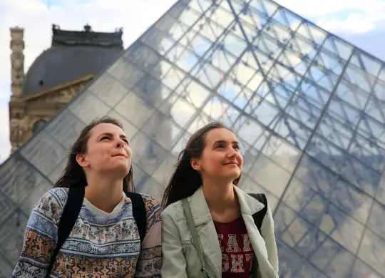 Auf Klassenfahrt mit HEROLÉ: Schülerinnen vor dem markanten Eingang des Louvre in Paris