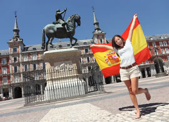 Altstadt in Madrid Auf Klassenfahrt mit HEROLÉ: Mädchen mit spanischer Flagge am Plaza Mayor in Madrid