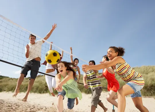 Auf Klassenfahrt mit HEROLÉ: Gruppe spielt am Strand eine Runde Beachvolleyball auf Rügen