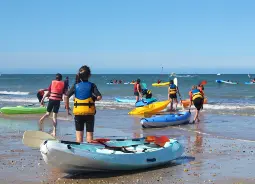 Auf Klassenfahrt mit HEROLÉ: Schülergruppe mit Kayaks am Strand