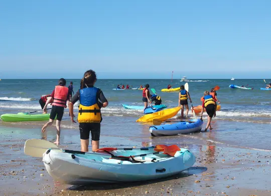 Auf Klassenfahrt mit HEROLÉ: Schülergruppe mit Kayaks am Strand