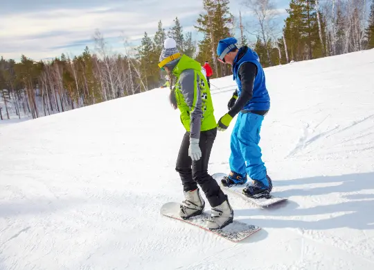 Snowboarder in Österreich Auf Klassenfahrt mit HEROLÉ: zwei Snowboarder auf der Piste in Österreich