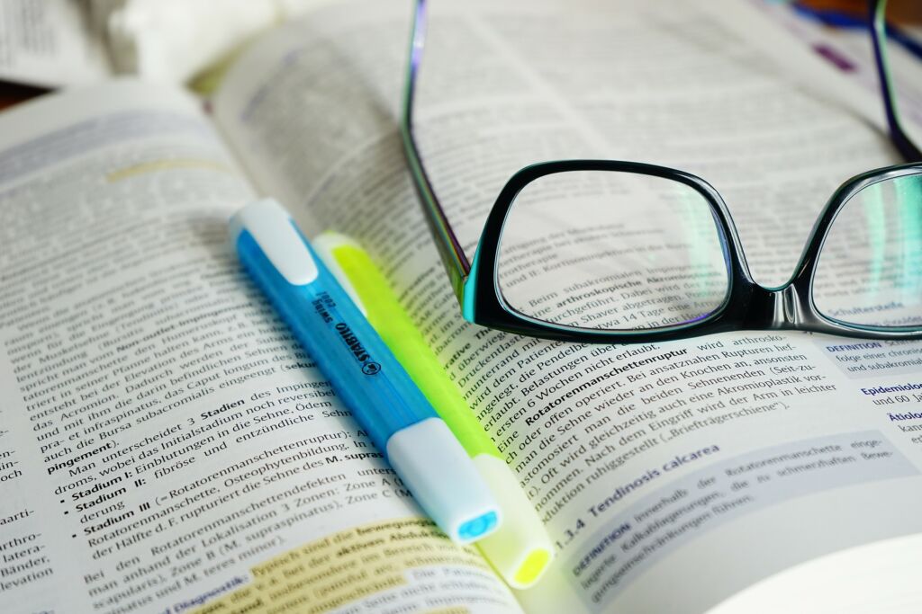 Textmarker und Brille auf Lernbuch.