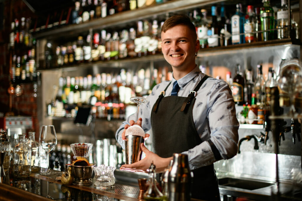 Student steht hinter der Bar und mixt Cocktails