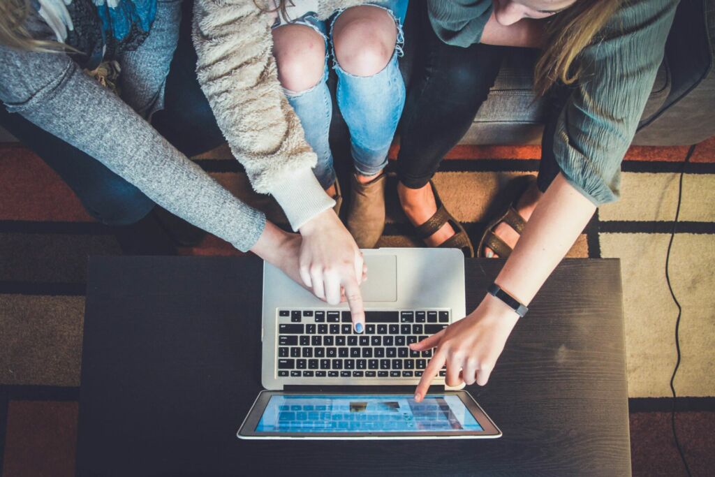 Dre Frauen sitzen vor dem Laptop und zeigen auf den Bildschirm