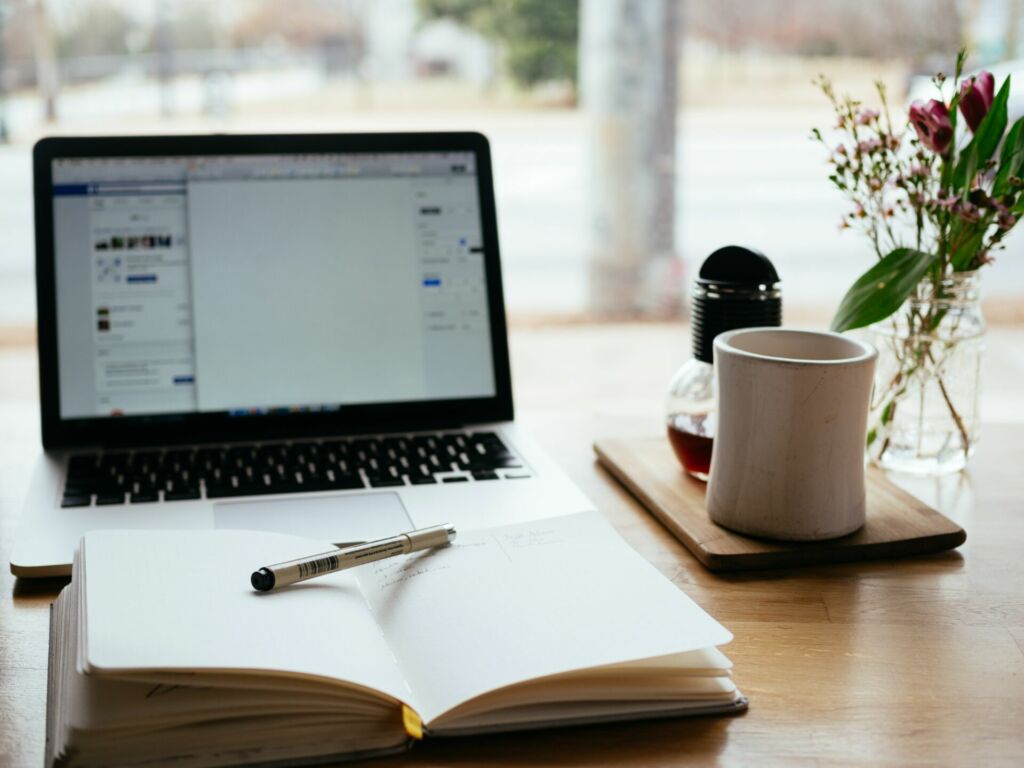 Ein Laptop und ein Notzizbuch liegen auf dem Tisch