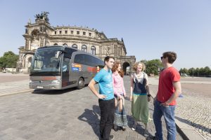 Einige Jugendliche vor einem firmeneigenen Bus