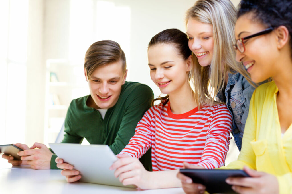 Vier jugendliche Schüler schauen auf Tablets.