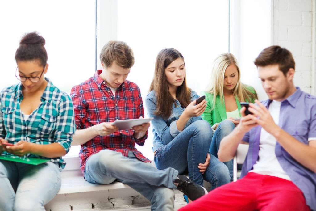 Jugendlichen an Handy und Tablet in der Schule.