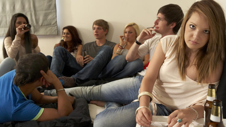 Jugendliche sitzen in einem Zimmer und rauchen und trinken