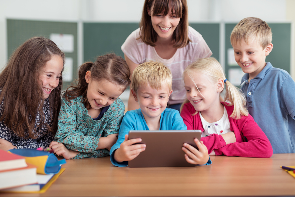 Blick auf eine Schülergruppe, die ein Tablet bedient