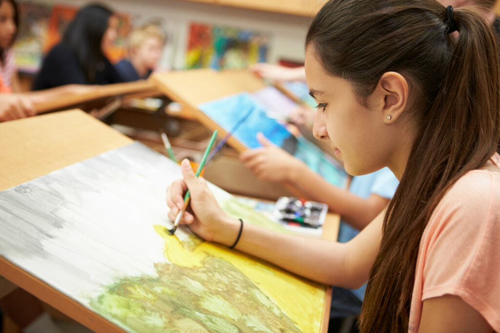 Eine Schülerin malt ein Bild im Kunstunterricht in der Schule.