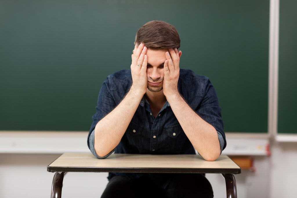 Blick auf einen Lehrer, der die Arme vor dem Kopf verschränkt