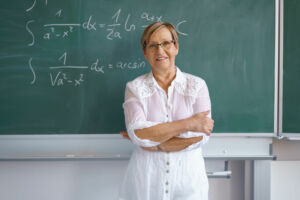 Mathelehrerin steht an einer Tafel im Klassenzimmer.