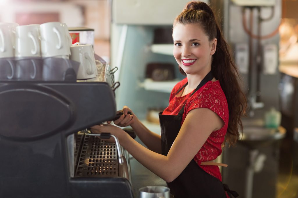 Blick auf ein Mädchen, das eine Kaffeemaschine bedient