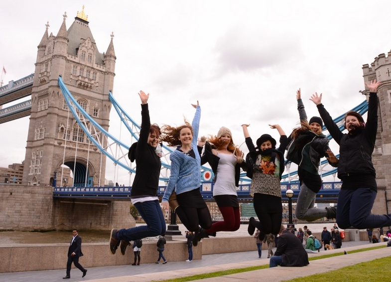 Mädchengruppe springt vor der Tower Bridge in London in die Luft