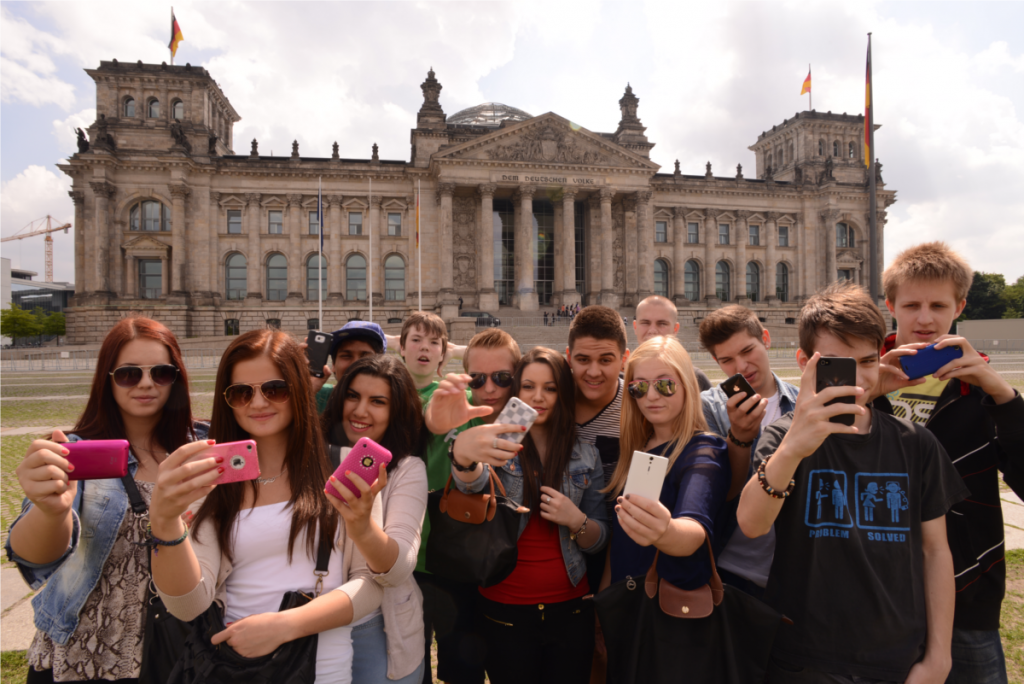 Eine Schülergruppe auf Klassenfahrt vor dem Bundestag in Berlin ein Selfie.