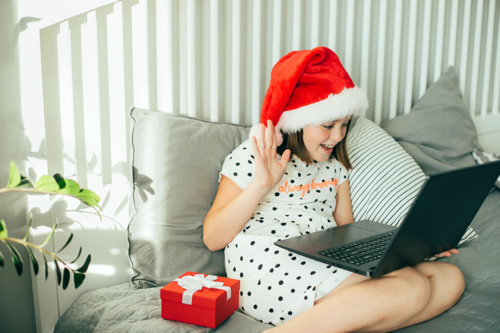 Eine junge Schülerin mit Weihnachtsmütze sitzt vor ihrem Laptop.