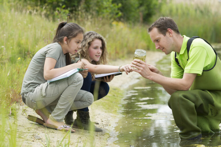 Zwei Schülerinnen unternehmen mit Ihrem Biologielehrer eine Exkursion und untersuchen Wasserproben